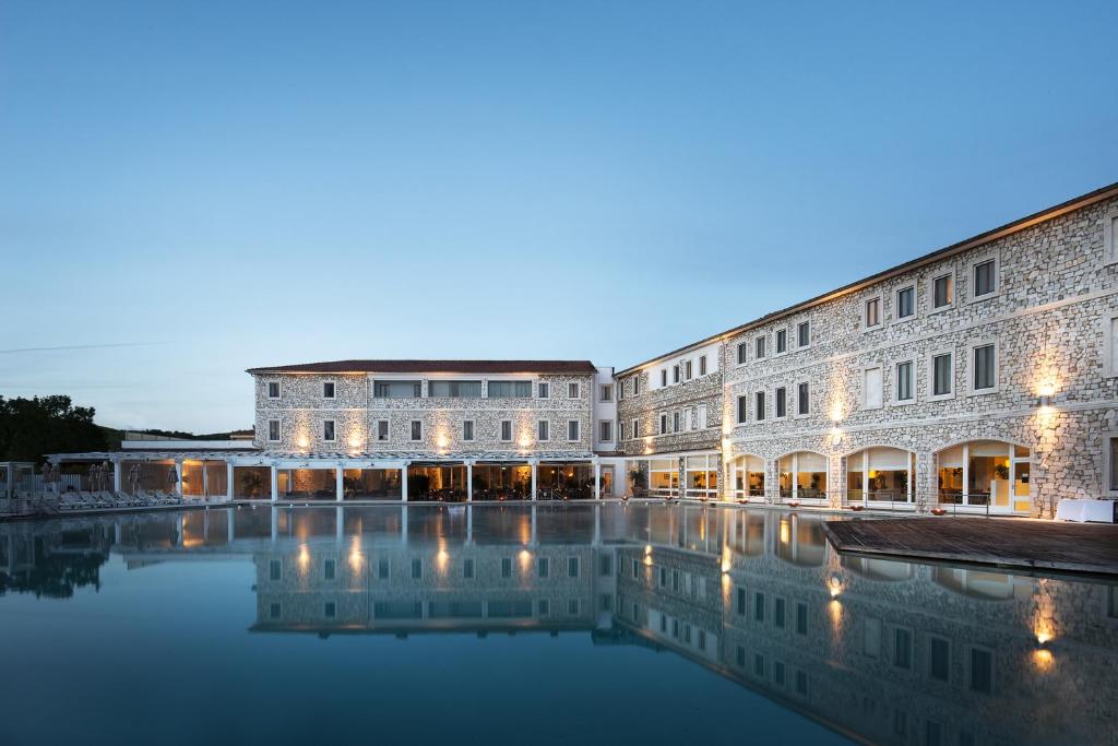 - un bâtiment avec une piscine d'eau en face dans l'établissement Terme di Saturnia Natural Spa & Golf Resort - The Leading Hotels of the World, à Saturnia