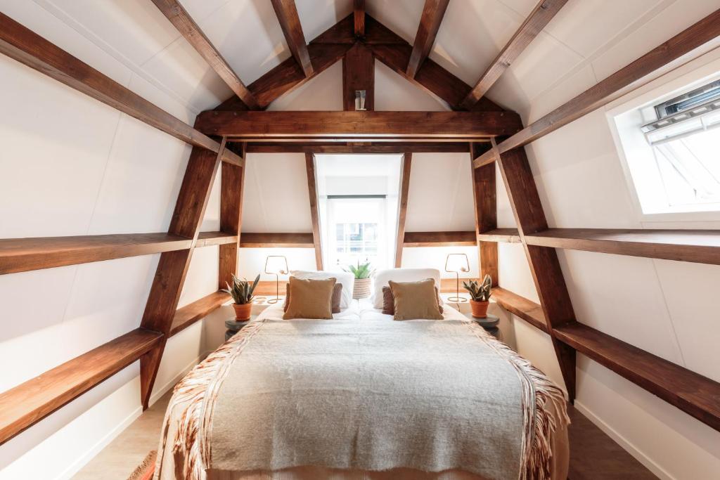 een slaapkamer met een groot bed in een kamer met houten plafonds bij Hotel Dwars in Amsterdam