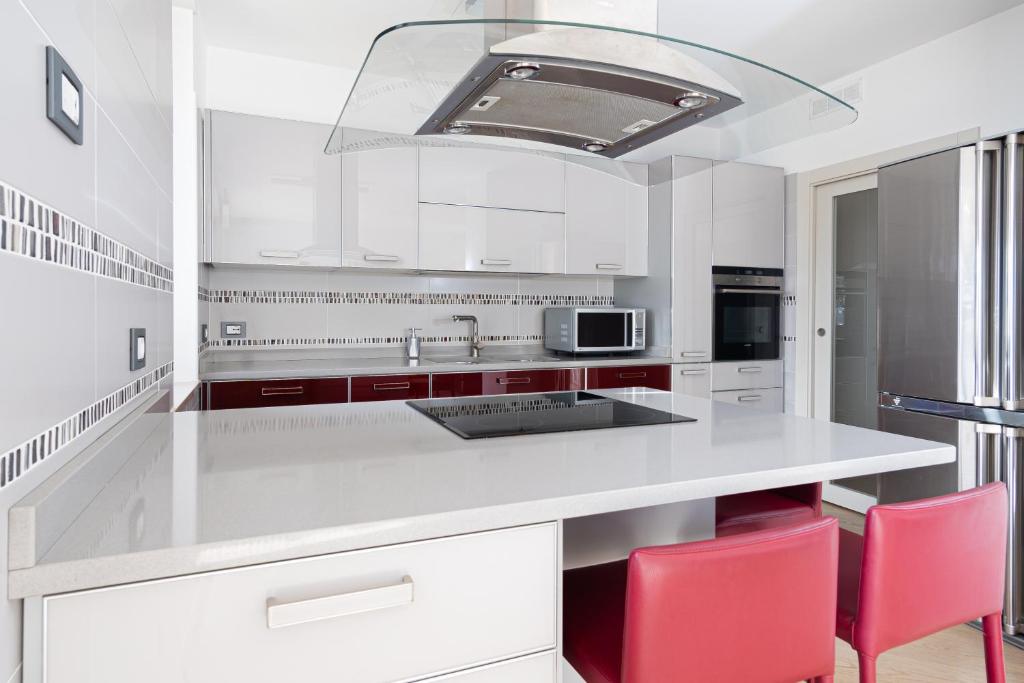 - une cuisine blanche avec des chaises rouges et un îlot de cuisine dans l'établissement Trento View, à Trente