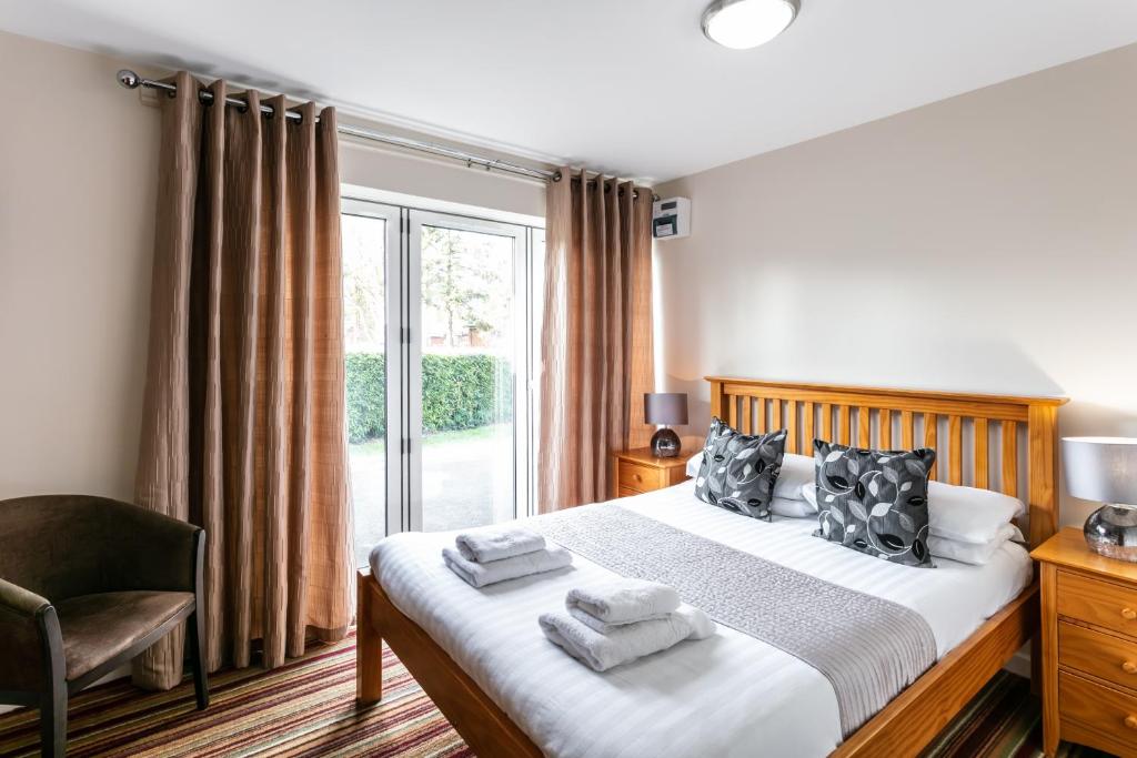 a bedroom with a bed and a chair and a window at Roydon Marina Village Hotel in Roydon