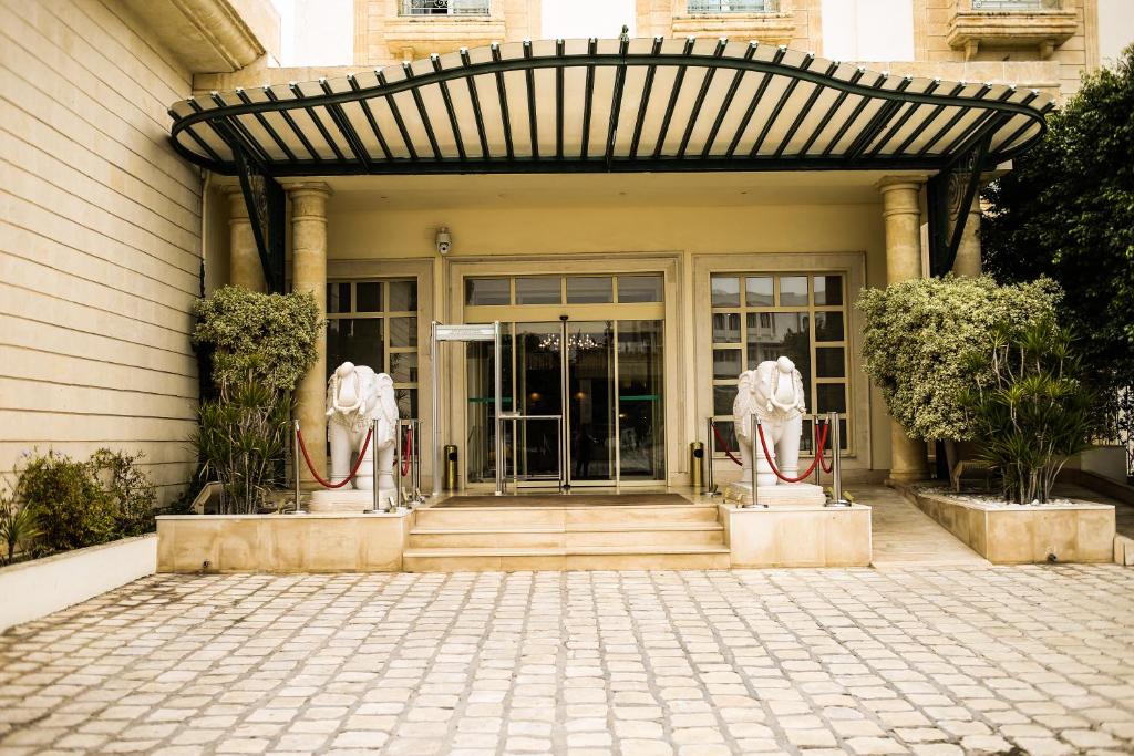 einer Eingangstür eines Gebäudes mit zwei Statuen in der Unterkunft Acropole Tunis in Tunis