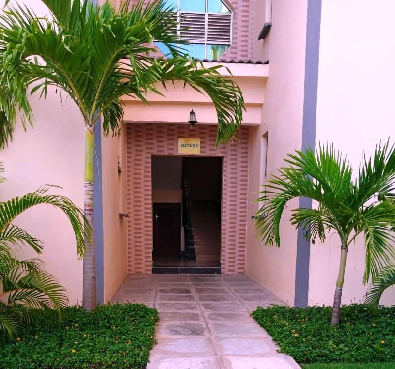 a building with palm trees in front of a hallway at BLUE NILE 9 - SUNSET HOLIDAY APARTMENTS, SHANZU - Mombasa in Mombasa