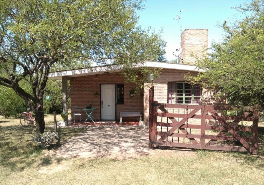 una casa de ladrillo con una puerta y una valla en Casa Dos, casita de campo en Alta Gracia