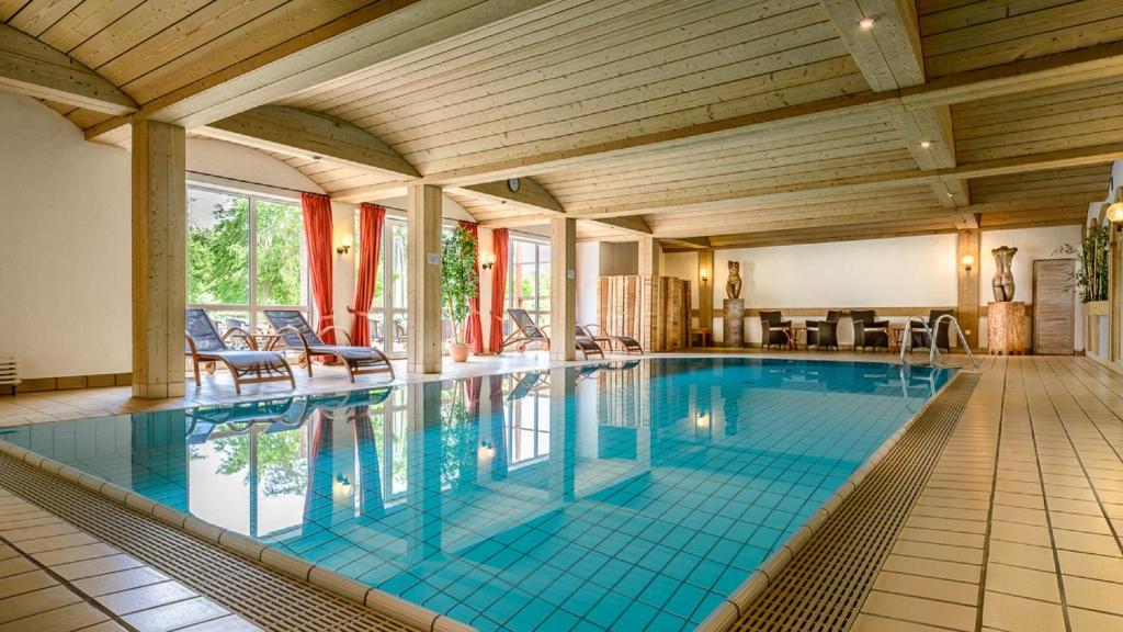 een groot zwembad met blauwe tegels in een huis bij Hotel Göller in Hirschaid