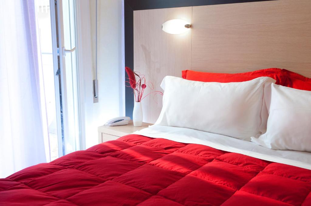 a red and white bed in a room with a window at Hotel Rubens in Rimini