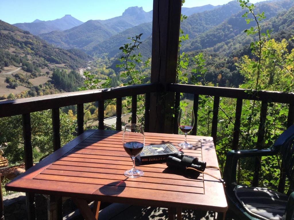 una mesa de madera con 2 copas de vino en el balcón en Olmares Apartamento Picos de Europa, en Pesaguero-La Parte