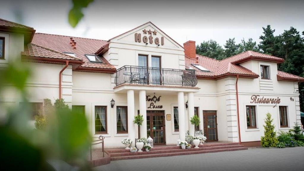 a large white building with a balcony at Dworek za Lasem in Warta