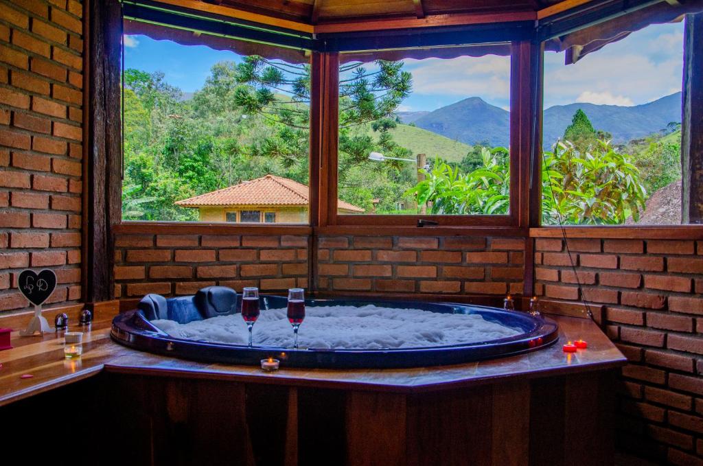 a bath tub in a room with a large window at Pousada Recanto Do Kaléo in Visconde De Maua