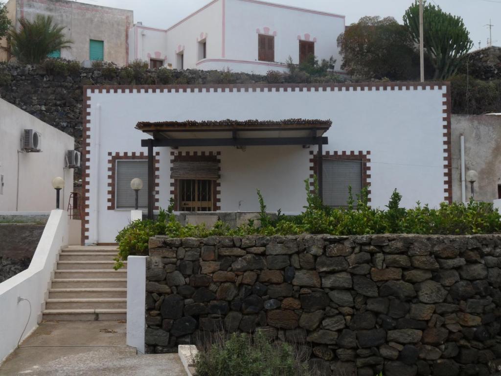 Casa blanca con pared de piedra y escaleras en Dammuso Tracino, en Pantelleria