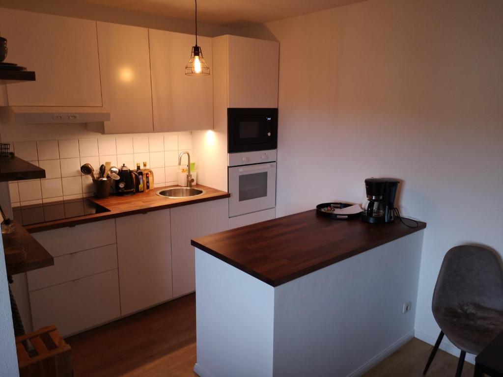 a kitchen with white cabinets and a wooden counter top at Ferienwohnung Schreckenbach in Sankt Egidien