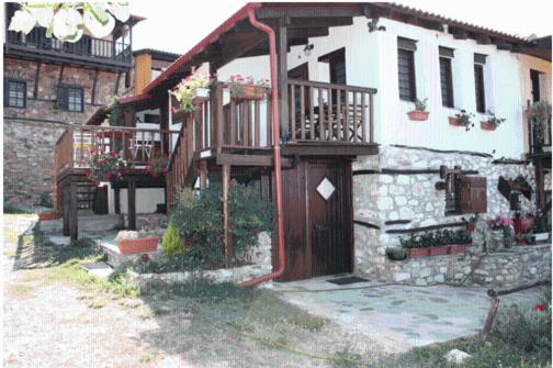 a house with a wooden door and a balcony at Guesthouse Eleni in Palaios Panteleimon