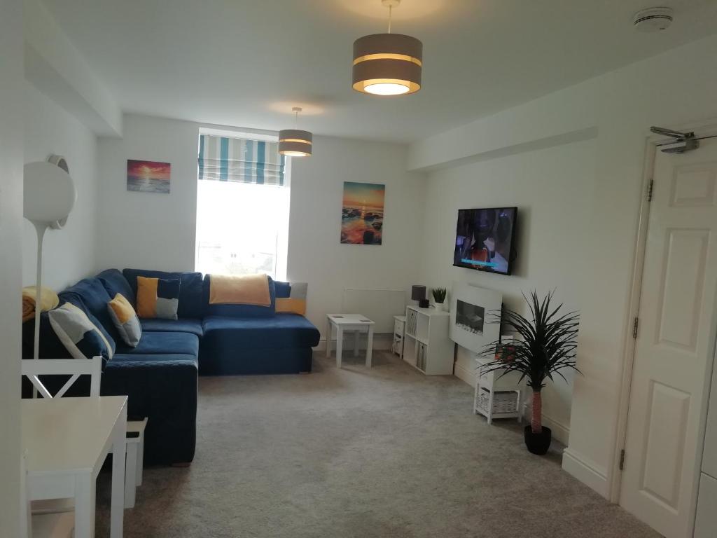 - un salon avec un canapé bleu et une table dans l'établissement Rhodri Apartment with Sea Views and Sun Terrace, à Trearddur