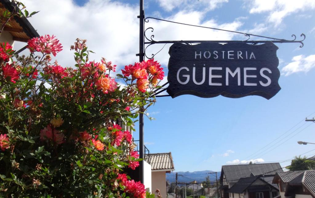 un cartello per un negozio di osteeria guernica con fiori di Hostería Güemes a San Carlos de Bariloche