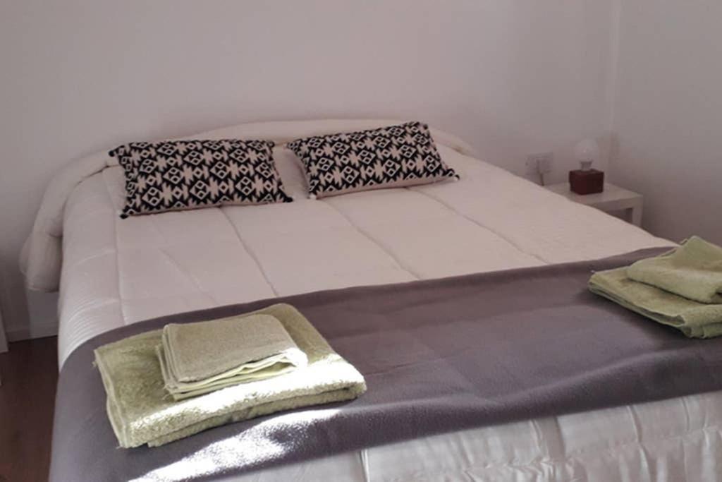 Una cama blanca con toallas en una habitación en aparts centro 2 ambientes en San Carlos de Bariloche