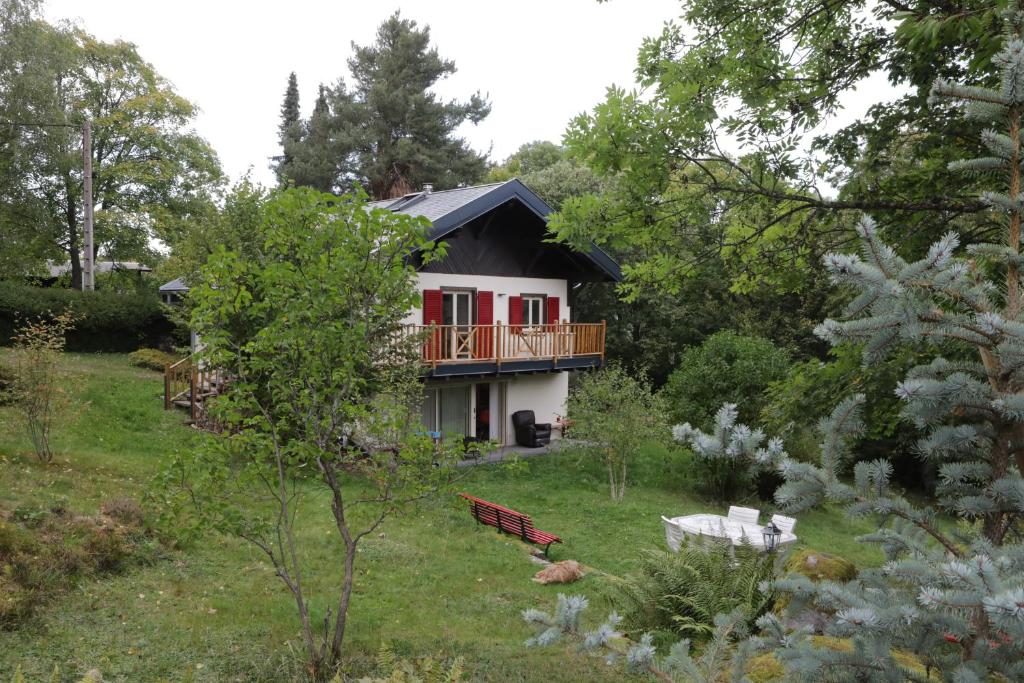 a house with a balcony in the middle of a yard at Chalet les airelles in Labaroche