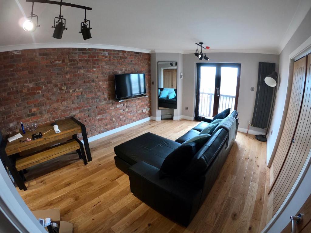 a living room with a black couch and a brick wall at 46 Y Lanfa in Aberystwyth