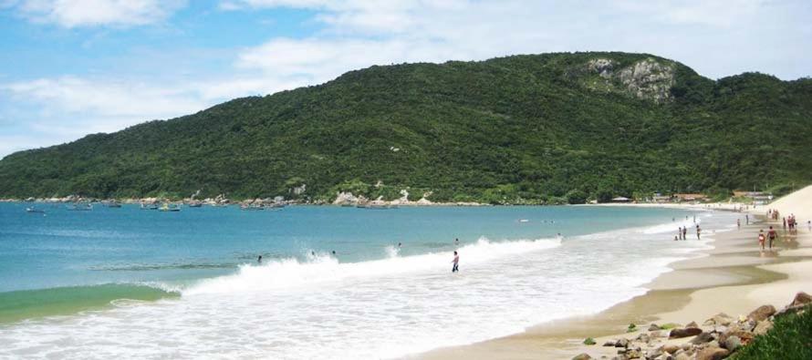 un grupo de personas en una playa con una montaña en Ilha do Coral Residence, en Florianópolis
