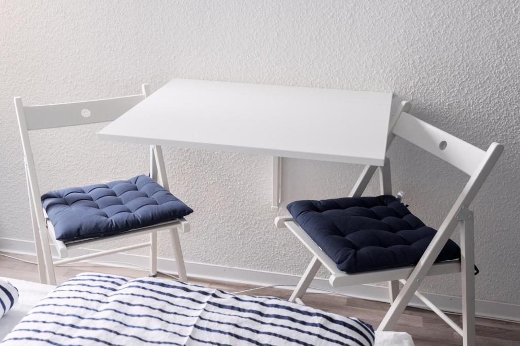 une table blanche et deux chaises à côté d'un lit dans l'établissement Kuschelige Ferienwohnung mit WLAN & Privatparkplatz, à Kaiserslautern