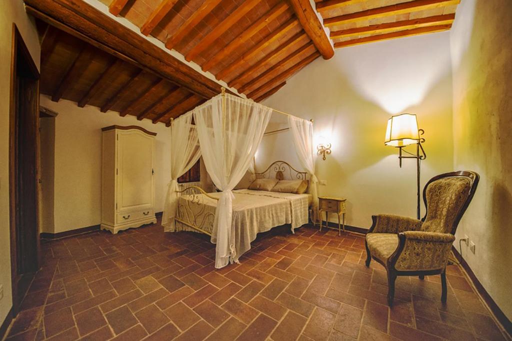 een slaapkamer met een bed en een stoel in een kamer bij La Terrazza sul Borgo - Montefioralle Apartment in Greve in Chianti