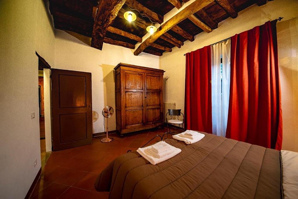 1 dormitorio con 1 cama y cortinas rojas en Il Papavero - Montefioralle Apartment en Greve in Chianti