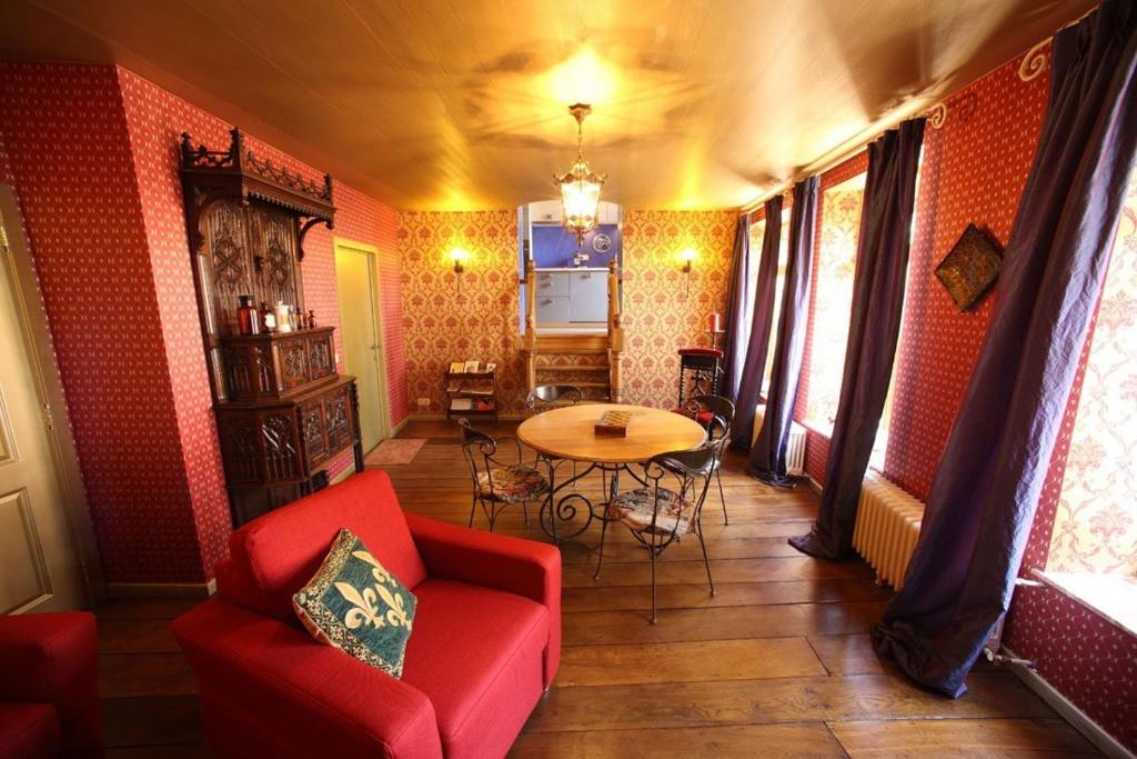 Gîtes d'Apothecarius entre Namur et Dinant في Fosses-La-Ville: غرفة معيشة مع أريكة حمراء وطاولة