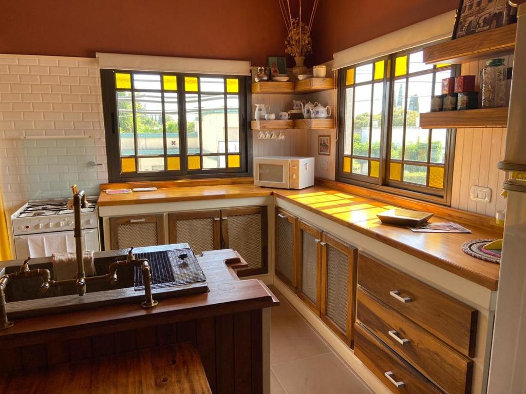 eine Küche mit Holzschränken, einem Waschbecken und Fenstern in der Unterkunft El Refugio in Lobos