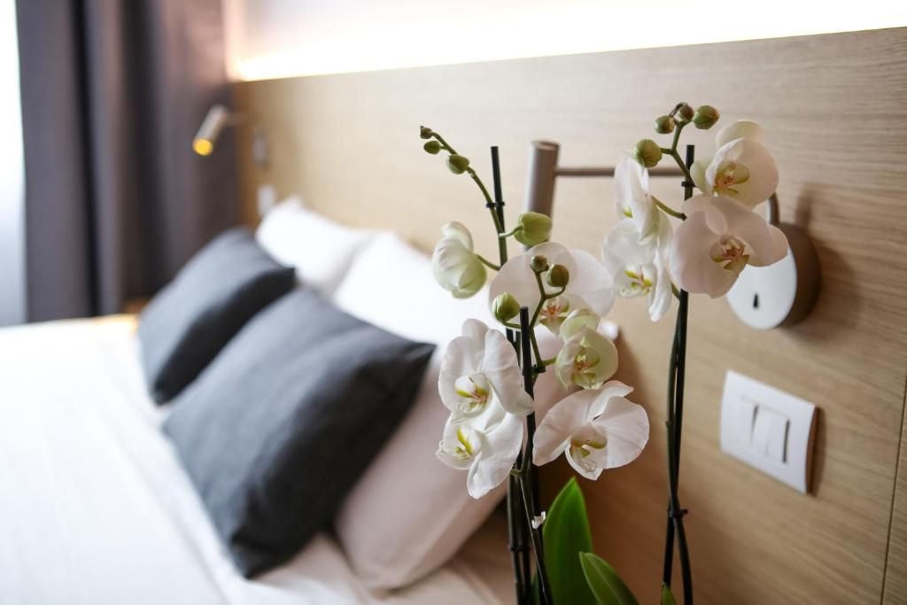 a vase filled with white flowers next to a bed at Bed and Bike Verona in Verona