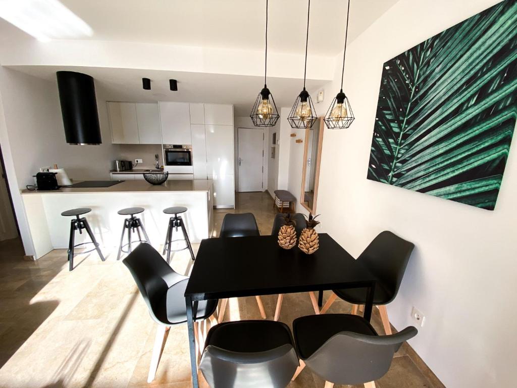 een eetkamer en een keuken met een zwarte tafel en stoelen bij Beautiful New Apartment with Sea View in Castillo de Sabinillas