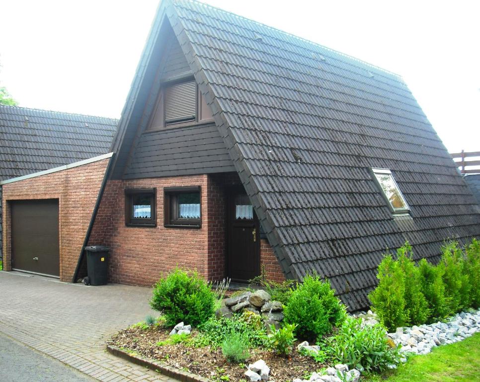 ein Haus mit einem schwarzen Dach und einem Garten in der Unterkunft Ferienhaus Mauer Krombachtalsperre, exclusive Nebenkosten Strom in Driedorf