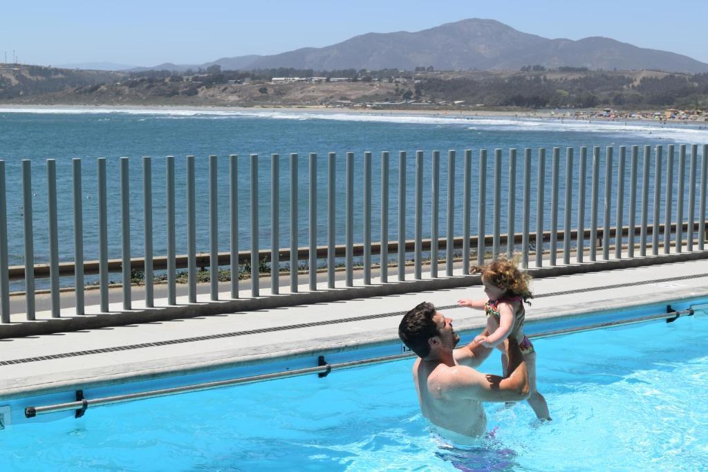 een man en een kind in een zwembad bij Pura Vida - nuevo apartamento con salida directa a la costa in Concón