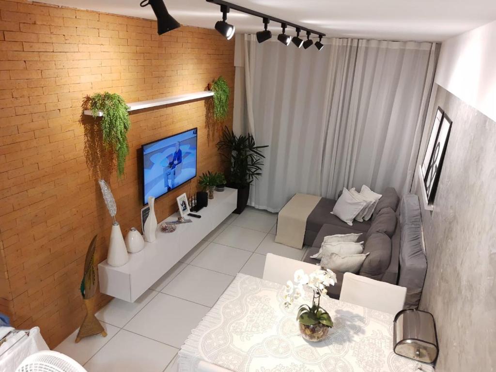 uma sala de estar com um sofá e uma televisão em QUARTO/SALA COM VISTA P/ O MAR DE PAJUÇARA em Maceió