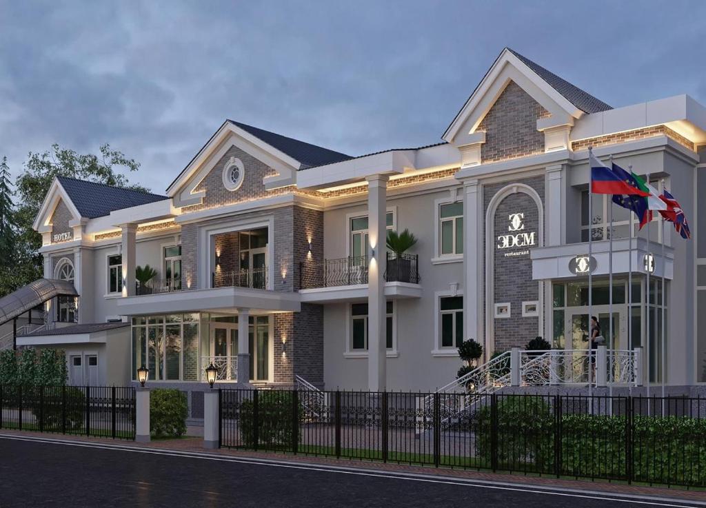 une grande maison avec un drapeau devant elle dans l'établissement EDEM Hotel, à Türkistan