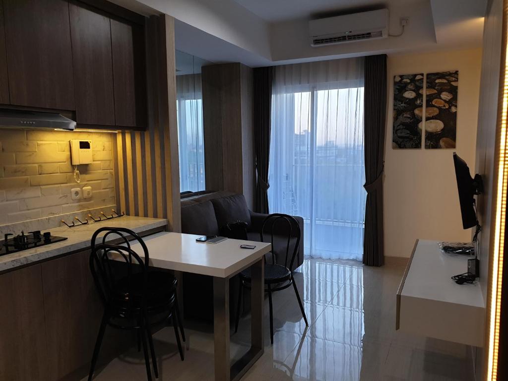 een keuken en eetkamer met een tafel en stoelen bij Apartemen Grand sungkono Lagoon Venetian. in Surabaya