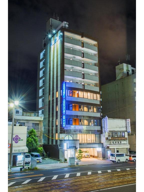 Un edificio alto con luces azules a los lados. en Sejour Inn Capsule, en Hiroshima