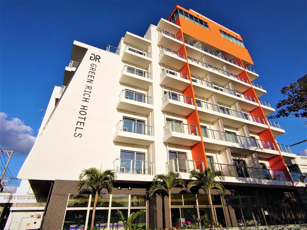 a hotel with an orange and white building at Green Rich Hotel Okinawa Nago (Artificial hot spring Futamata Yunohana) in Nago