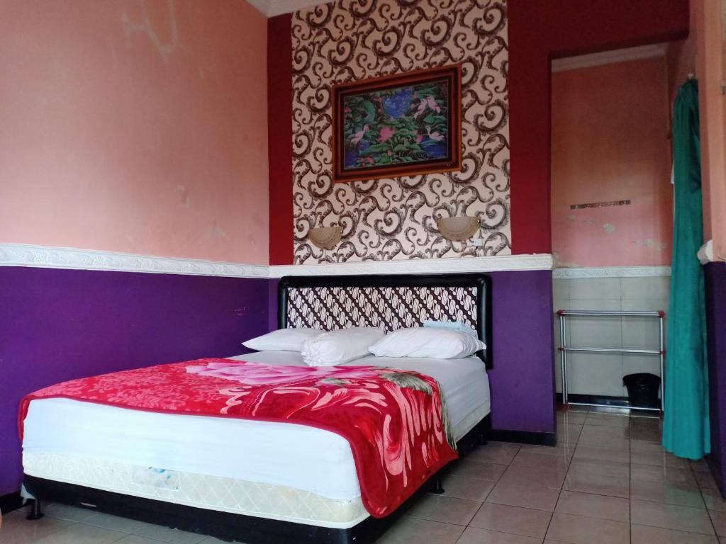a bedroom with a bed with a red blanket on it at OYO 3020 Penginapan Citra Rasa in Sarangan