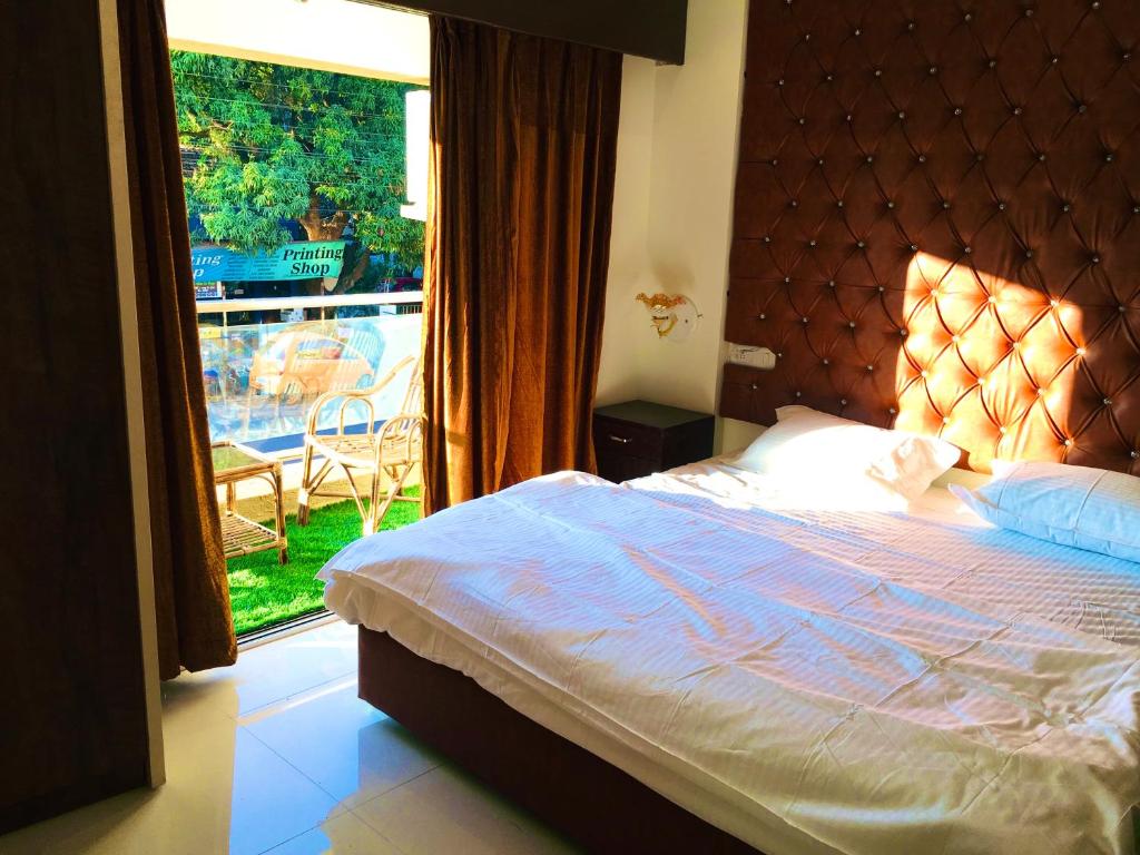 a bedroom with a bed and a large window at kesinovo suites in Anjuna