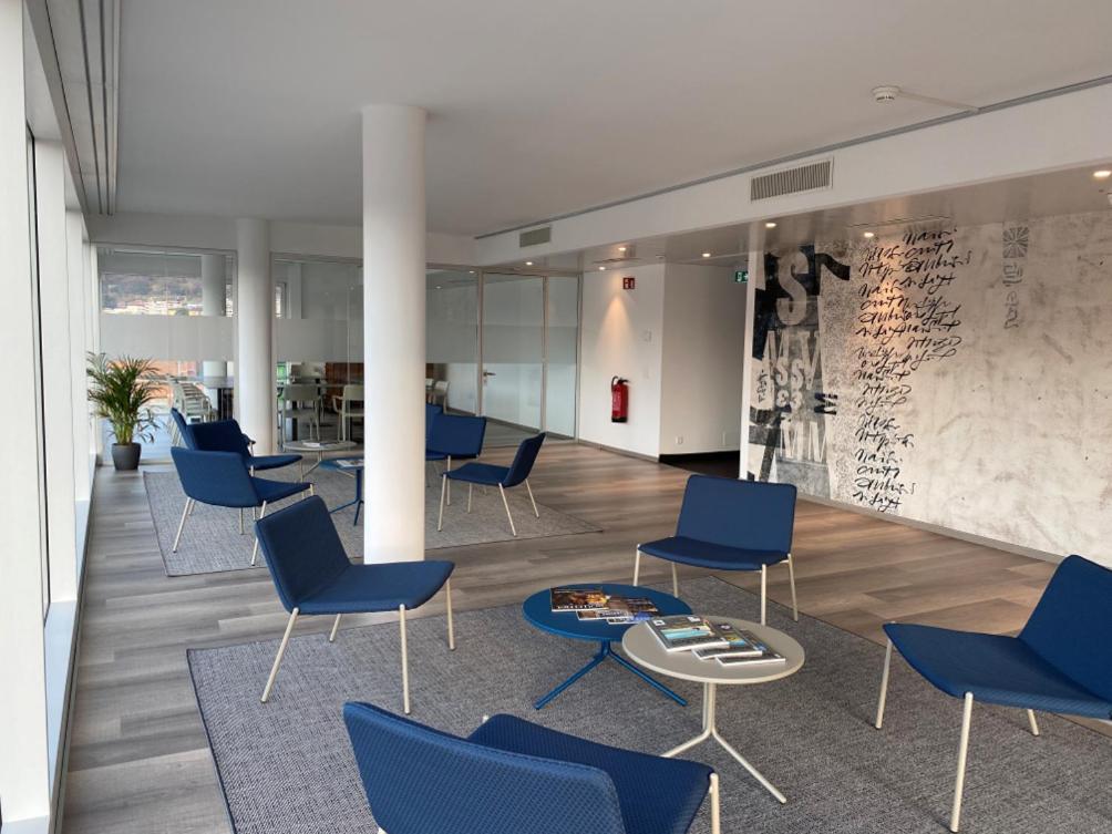 a lobby with blue chairs and a table at Hotel Albergo Milano in Mendrisio