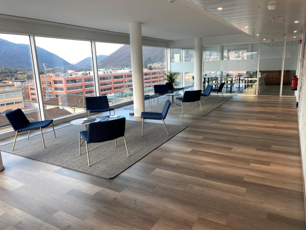 an empty office with chairs and tables and windows at Hotel Albergo Milano in Mendrisio