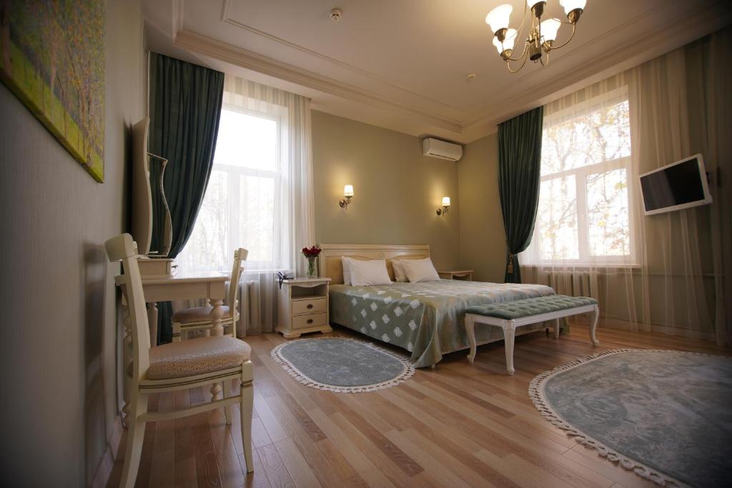 a bedroom with a bed and a chair and windows at Grand Kavkaz Hotel in Nalchik