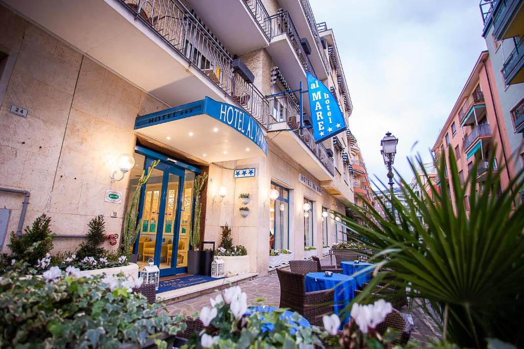 a building with blue tables and chairs on a street at Hotel Nuovo Al Mare in Alassio