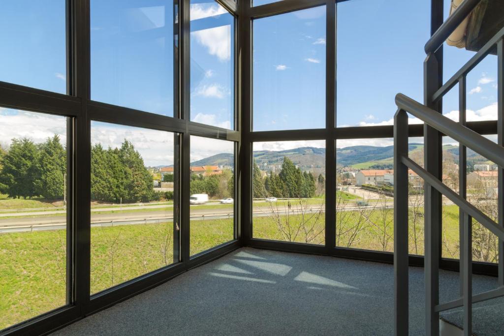 a room with large windows with a view of a street at The Originals City, Hôtel L&#39;Acropole, Saint-Etienne Sud (Inter-Hotel) in La Ricamarie