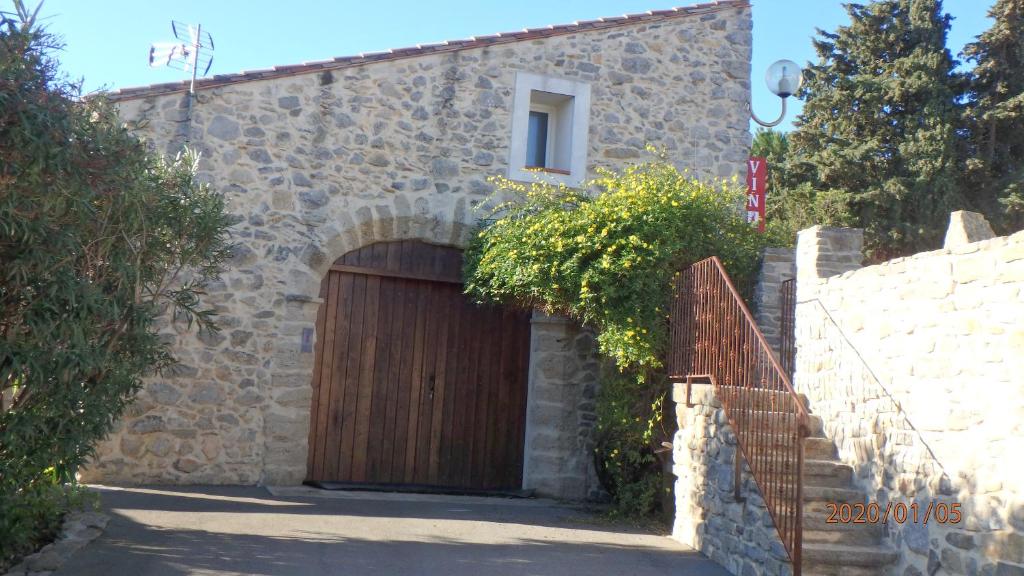 a stone building with a wooden garage door at Maison Bergerie Glabanel in Lapalme