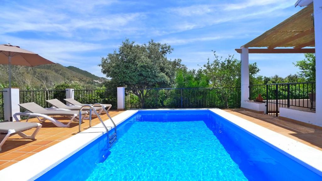 - une piscine avec des chaises et un parasol à côté d'une maison dans l'établissement Villa Jazmin - C&G, à Frigiliana