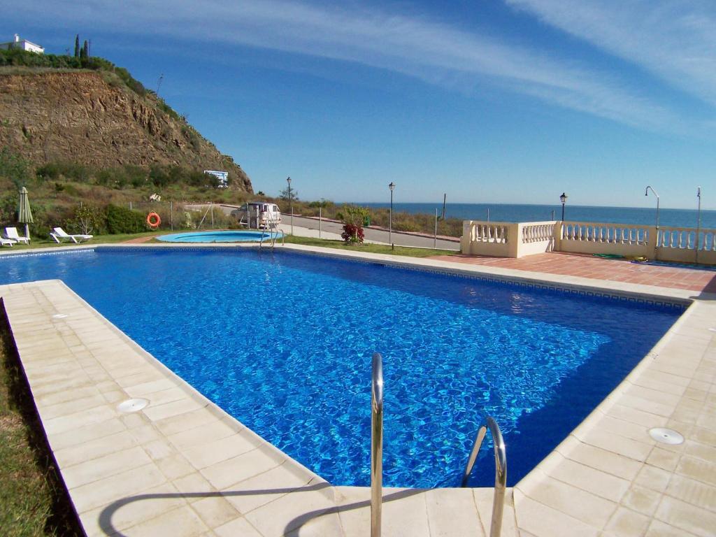 a large blue swimming pool with the ocean in the background at Torrox Beach Club in Torrox Costa