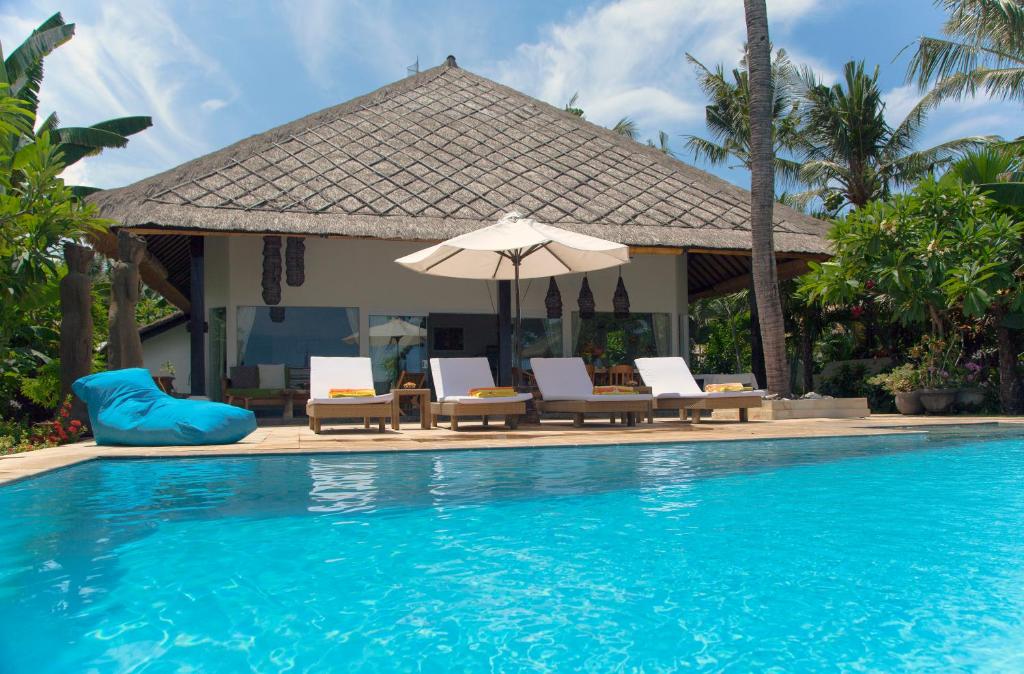 uma piscina com cadeiras e um guarda-sol em Villa Paradise Lovina em Temukus