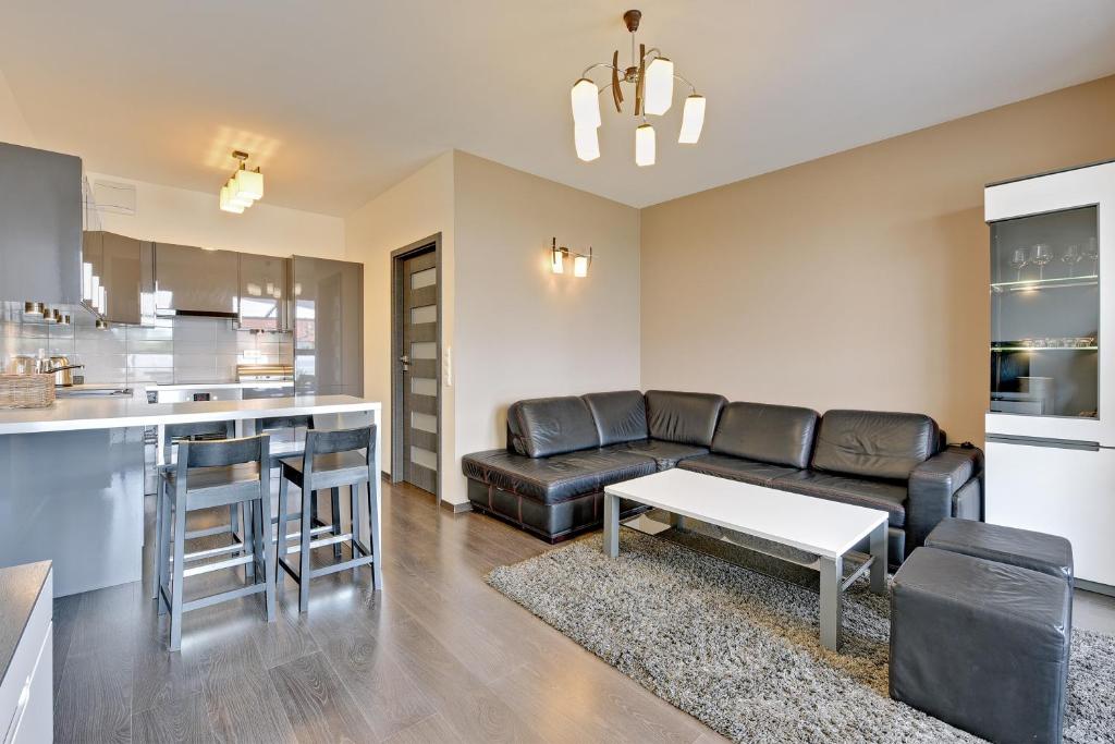 a living room with a black couch and a kitchen at Downtown Apartments Hallera 165 in Gdańsk