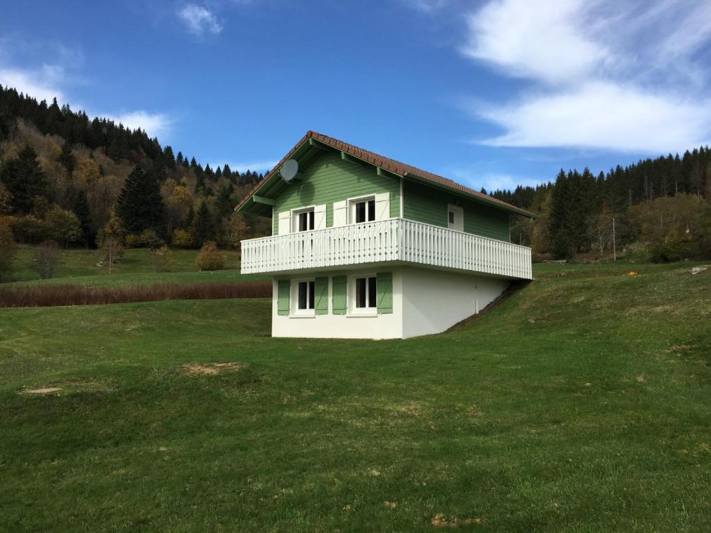 uma casa verde e branca num campo de relva em La Bresse Hautes Vosges Chalet le Paiquis em La Bresse