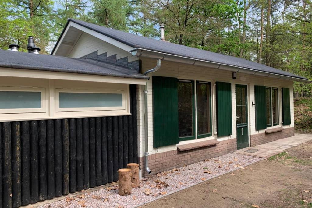 ein Haus mit einem schwarzen Zaun davor in der Unterkunft Tine Boshuisje Veluwe in Otterlo