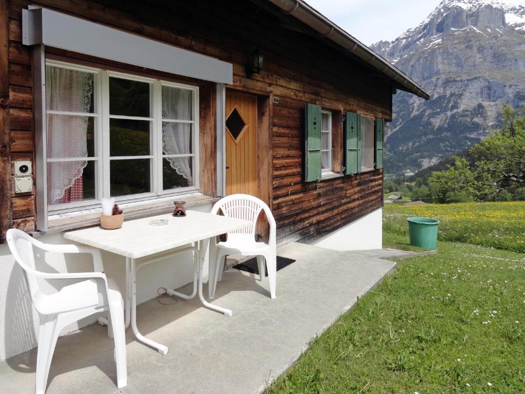 una mesa y sillas blancas fuera de una cabaña en Ferienwohnung im Grünen, en Grindelwald